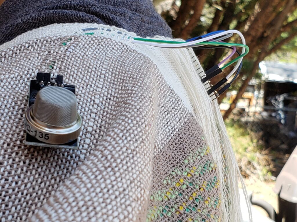 Shot of one shoulder of the vest, showing the wiring of one air quality sensor to a central processor.